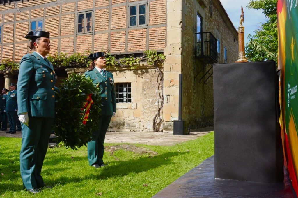Dos guardias civiles portan una corona de laurel durante el homenaje a los agentes fallecidos en el acto de la patrona en Camargo.