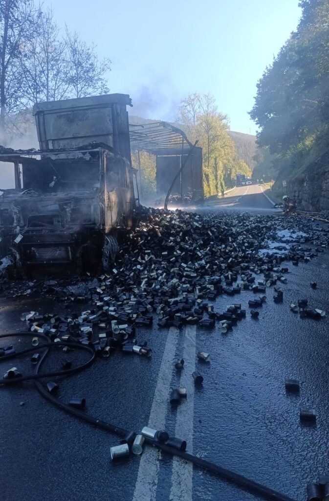 Camión calcinado y latas de conserva vacías esparcidas por la calzada de la N-623 tras el incendio en Luena.