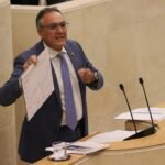 Raúl Pesquera muestra una estadística sobre la esperanza de vida desde la tribuna del Parlamento de Cantabria.